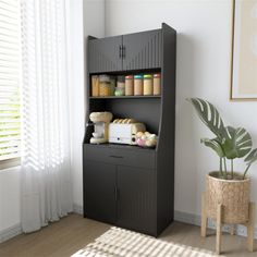 a black cabinet with some items on it in a room next to a potted plant