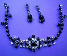 This fabulous glitzy demi is a deep black stone piece accented with clear rhinestones that form a lovely center piece to the necklace, which is accented in the pierced dangle earrings.   The center of the necklace, which consists of a square stone, surrounded by smaller round black and clear stones, is stationary and 2½ inches in length.  The black crystal single strand necklace extends up the piece to the clasp for a total length of 15 inches but it can be worn shorter if so desired.   The pierced dangle earrings are 1¼ inch drop. These pieces are in excellent condition and are from a recent estate sale.  Please view my shop often as I continually add new and interesting items. Thanks for looking and visiting my shop. Glamorous Black Rhinestone Jewelry, Glamorous Black Jewelry With Sparkling Stones, Black Rhinestone Crystal Necklace, Black Rhinestone Dangle Jewelry, Black Dangle Jewelry With Rhinestones, Black Dangle Rhinestone Jewelry, Black Jewelry With Sparkling Stones For Party, Black Rhinestone Costume Jewelry, Formal Black Jeweled Jewelry