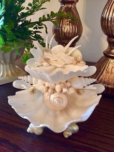 a vase with shells and flowers in it sitting on a table next to two other vases