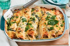 a casserole dish with spinach and cheese in it on a cutting board