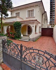 a large house with a gate in front of it and some bushes on the other side