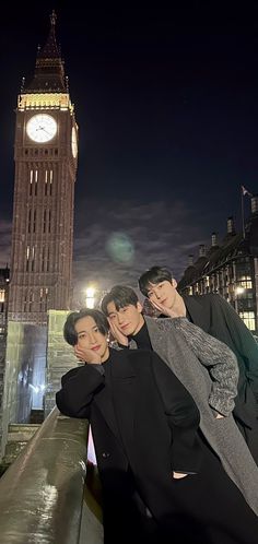 three people standing in front of a clock tower