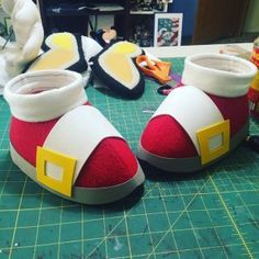 two pairs of shoes sitting on top of a cutting board next to scissors and other crafting supplies