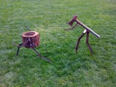 two wooden chairs sitting on top of a lush green field next to a tree stump