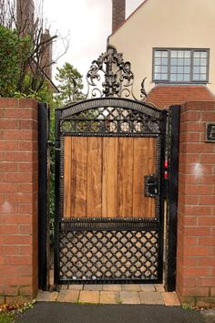 an iron gate with wooden door and brick wall in front of a house on a cloudy day