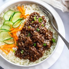 a white bowl filled with rice, meat and cucumber garnishments