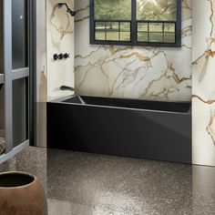 a bath tub sitting under a window next to a sink in a room with marble walls