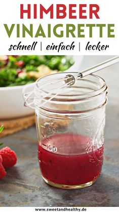 a jar filled with raspberry vinaigrete next to a bowl of berries