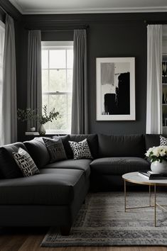 a living room with black couches and white curtains on the window sill,