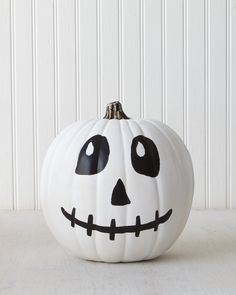 a white pumpkin decorated with black and white faces