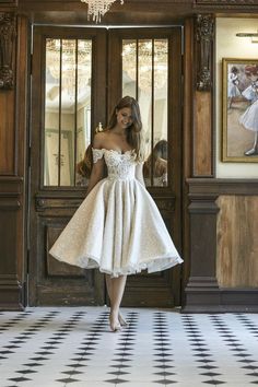 a woman standing in front of a doorway wearing a white dress