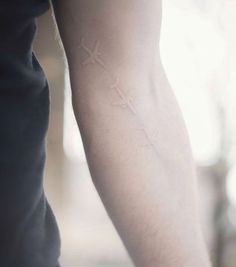 a person with a cross tattoo on their arm