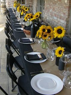 the table is set with sunflowers in vases and empty plates on it