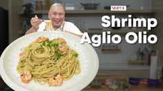 a man holding a plate with shrimp and pasta on it