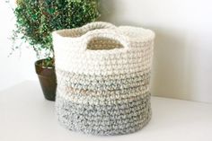 a crocheted basket sitting next to a potted plant