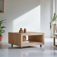 a coffee table with two vases on it and a plant in the corner next to it