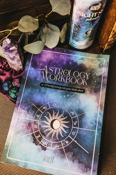 the astrology workbook sits next to two cans of beer and a plant on a table