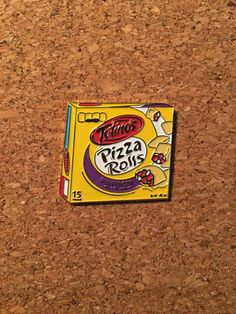 a box of pizza rolls sitting on top of a corkboard floor next to a wall