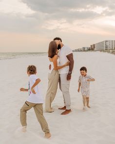 a woman and two children are playing on the beach with their mother in front of them