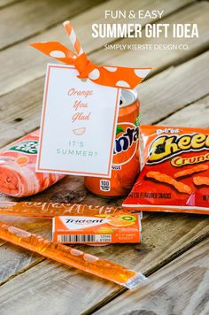 an orange and white gift bag with some candy on the table next to it is a sign that says, fun & easy summer gift idea simply hersie design co