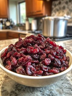 a white bowl filled with cranberries sitting on top of a counter next to an oven