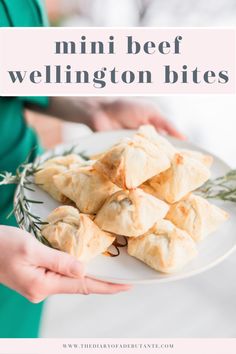 a person holding a plate full of mini beef wellington bites with rosemary sprigs