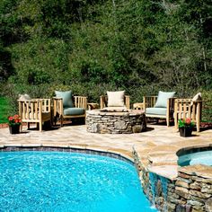 a backyard with a pool, fire pit and patio furniture set up next to it