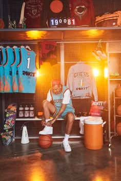 a man sitting on top of a basketball court next to a locker room filled with shirts