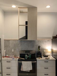 a kitchen with white cabinets and stainless steel stove top oven in the middle of it