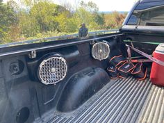 the back end of a pickup truck with speakers in it's bed and an orange cooler