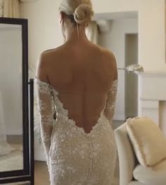 the back of a woman's wedding dress is shown in front of a mirror