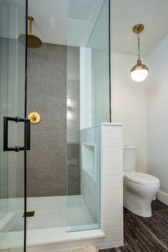 a white toilet sitting next to a shower in a bathroom on top of a hard wood floor