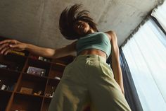 a woman standing in front of a bookshelf with her arms stretched out to the side