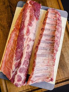 two pieces of meat sitting on top of a cutting board