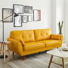 a living room with yellow leather couches and pictures on the wall above it,