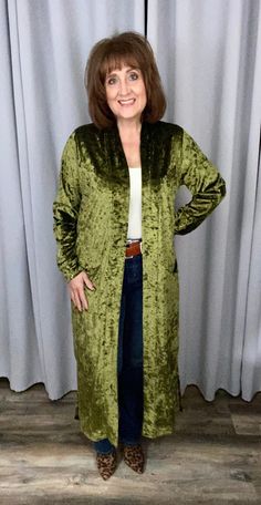 A long duster coat made from rich velvet makes any outfit more luxe in mere seconds. Styled with a shawl collar, cuffed sleeves, 11" side vent openings and front patch pockets, this olive crushed velvet beauty is just the ticket for adding plush texture to your outfit. The contrasting lining makes this piece a real show stopper. Top your favorite graphic tee, cami or mock neck. Pair it with joggers, straight leg or flair bottoms. It will even amp up vegan leather! Contrasting lining through the Long Duster Coat, Velvet Duster, Long Duster, All Love, Crushed Velvet, Shawl Collar, Cuff Sleeves, Love Is All, Mock Neck