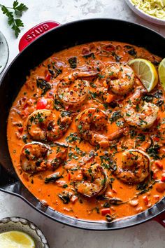 creamy garlic shrimp skillet in a red sauce with lemon wedges and parsley