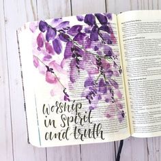 an open bible with purple flowers on it