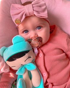 a baby with a pacifier laying next to a stuffed animal