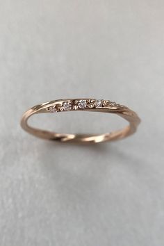 a gold wedding band with five diamonds on the top and bottom, sitting on a white surface