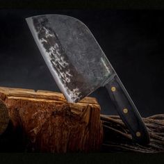 a large knife sitting on top of a piece of wood next to a tree stump