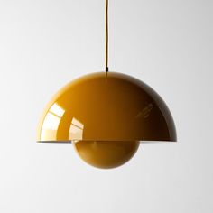 a yellow light hanging from a ceiling with a white wall in the backround