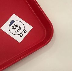 a red tray with a sticker on the lid that has a skull and crossbones drawn on it