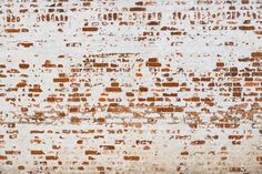 an old brick wall is painted white and brown