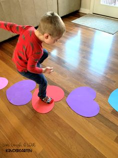 a young boy standing on top of a wooden floor in front of hearts cut out of paper