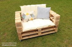 a couch made out of wooden pallets sitting on top of a grass covered field