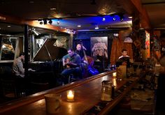 a group of people sitting at a bar with guitars in front of the bar counter