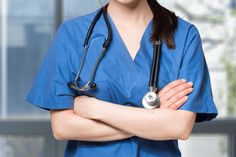 a woman in blue scrubs is standing with her arms crossed and wearing a stethoscope