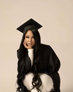 a woman with long black hair wearing a graduation cap and gown