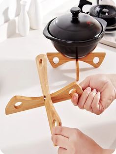 a person holding a wooden object in front of a pot and pan on a stove